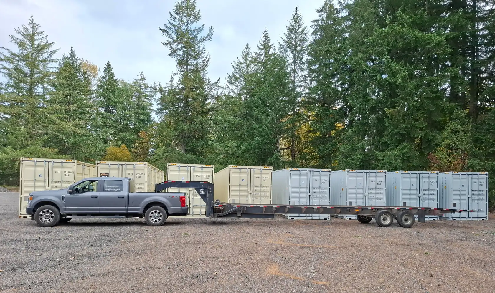 Pickup truck and gooseneck trailer parked in front of a row of shipping containers in a gravel yard
