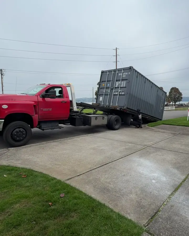 Shipping container riding up the tilt bed as the bed starts to level